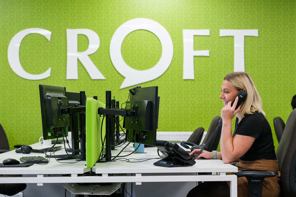 Croft expert working in our Midlands office at a PC while talking on a telephone.