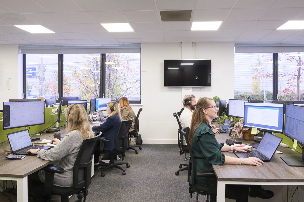 Croft meet the team employees working in an open plan office at their desktop computers.