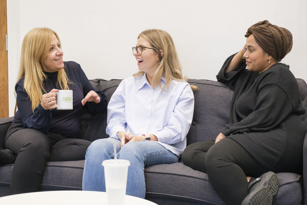 Three Croft Rewards employees sitting on a sofa having a conversation over a cup of tea.